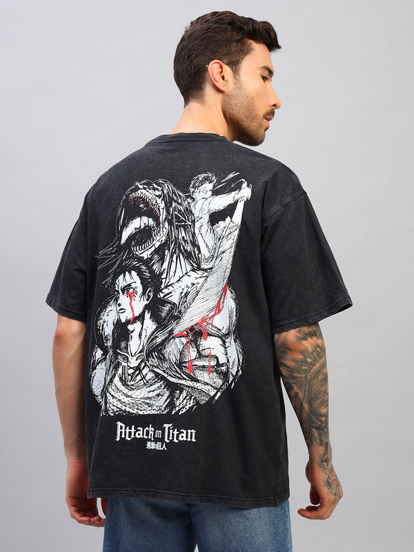 Man wearing a black t-shirt with 'Attack on Titan' graphic design on the back, standing against a gray background.